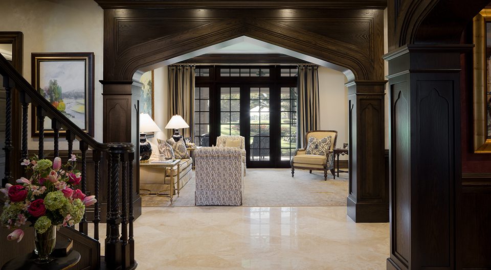 Entry hall with a dark wood arch and staircase opening onto a bright living room